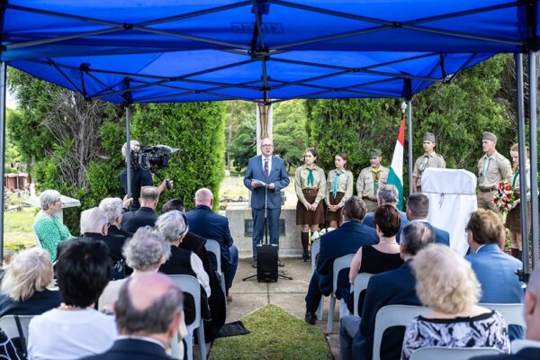 grief-care-memorial-service-speaker-addressing-gathering-under-canopy